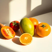 Una zanahoria, un mango, un tomate, un pomelo, naranjas y un mango verde representando las notas olfativas del perfume.